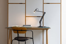 Anglepoise Navigation Edition Lamp sits on a desk table and illuminates the wall behind it